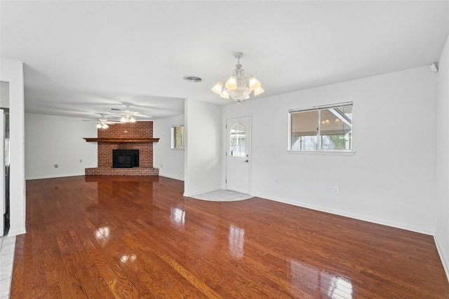 unfurnished living room featuring a fireplace, ceiling fan with notable chandelier, and hardwood / wood-style flooring