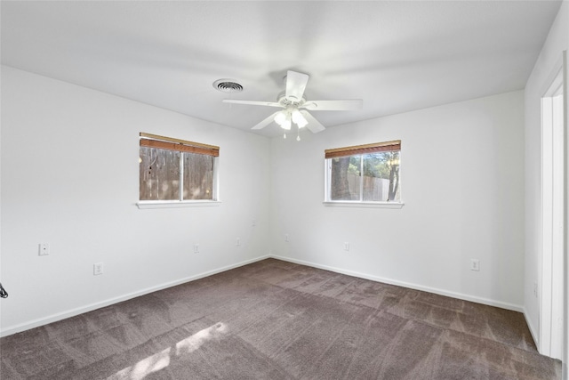 empty room featuring ceiling fan and dark colored carpet