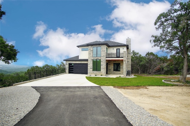 view of front of property featuring a balcony, a front yard, and a garage