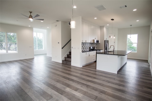 kitchen featuring a center island with sink, sink, dark hardwood / wood-style floors, white cabinetry, and decorative light fixtures