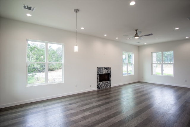 unfurnished living room featuring plenty of natural light, dark wood-type flooring, and ceiling fan