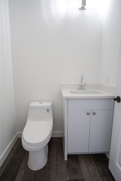 bathroom featuring toilet, vanity, and hardwood / wood-style floors