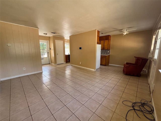 unfurnished living room with a textured ceiling, light tile patterned floors, and ceiling fan