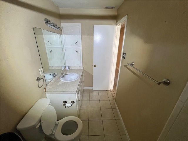 bathroom with toilet, vanity, and tile patterned floors