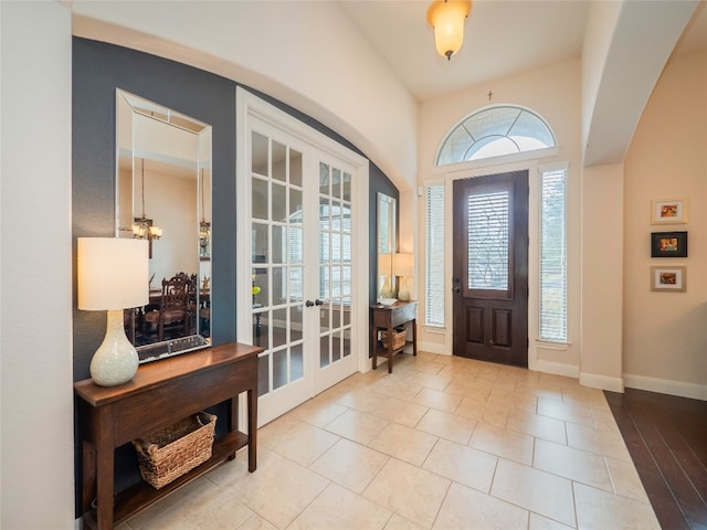 entryway with french doors, a notable chandelier, and light tile patterned floors