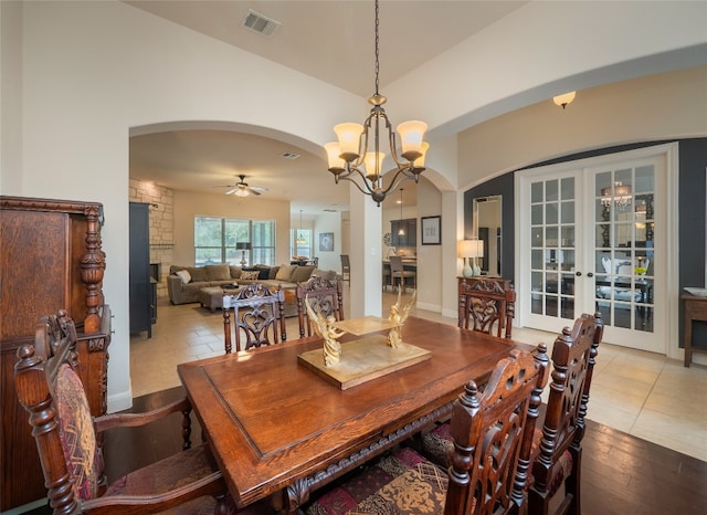 dining room with ceiling fan with notable chandelier, light wood-type flooring, and vaulted ceiling