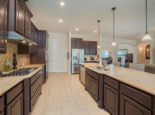 kitchen featuring dark brown cabinetry, sink, backsplash, pendant lighting, and appliances with stainless steel finishes