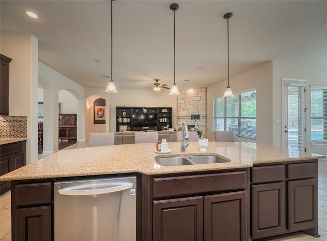 kitchen featuring dark brown cabinetry, stainless steel dishwasher, sink, and light stone countertops