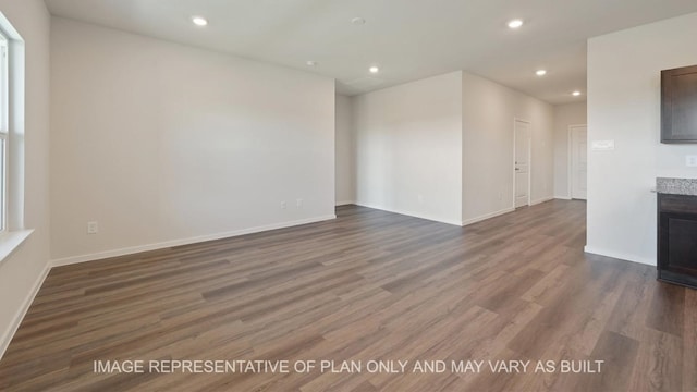 unfurnished room featuring a tiled fireplace and dark hardwood / wood-style flooring