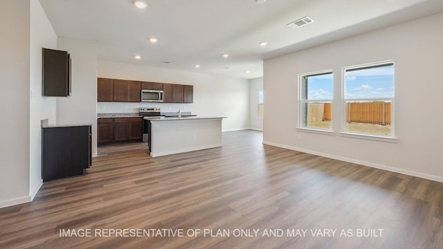 kitchen featuring stainless steel appliances, wood-type flooring, sink, and an island with sink