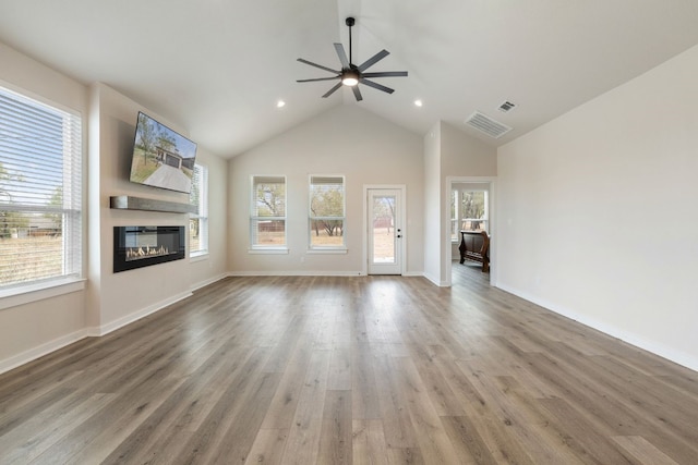 unfurnished living room with high vaulted ceiling, ceiling fan, hardwood / wood-style floors, and a healthy amount of sunlight