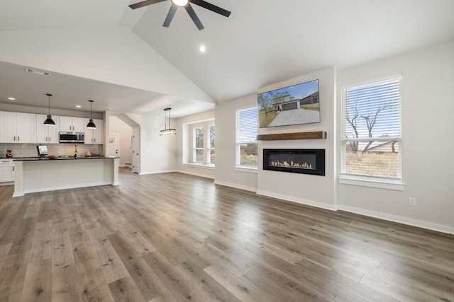 unfurnished living room featuring high vaulted ceiling, hardwood / wood-style flooring, and ceiling fan