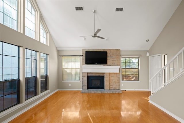 unfurnished living room with ceiling fan, high vaulted ceiling, light hardwood / wood-style floors, and a brick fireplace