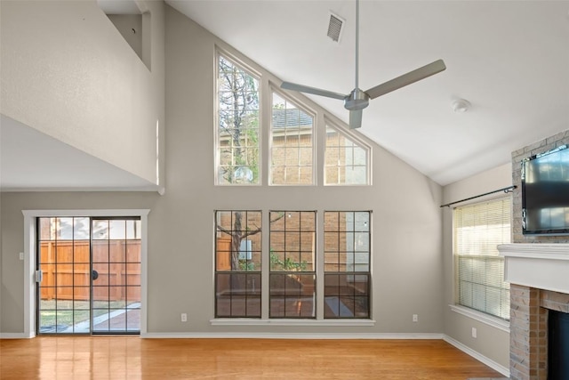 11310 Spicewood Club Dr Unit 10, Austin, TX 78750 - unfurnished living room featuring high vaulted ceiling, wood finished floors, a brick fireplace, and baseboards