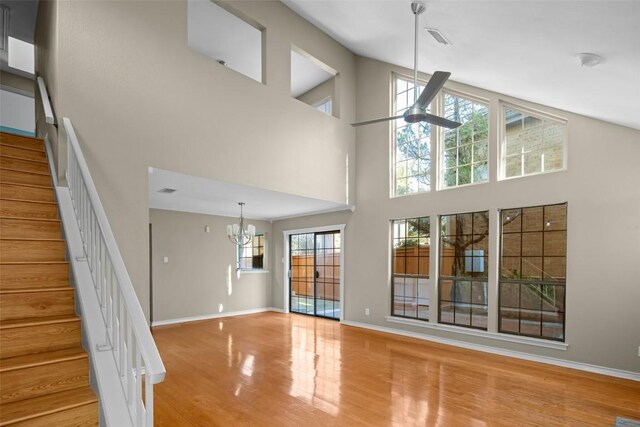 11310 Spicewood Club Dr Unit 10, Austin, TX 78750 - unfurnished living room featuring wood finished floors, a chandelier, a towering ceiling, baseboards, and stairway
