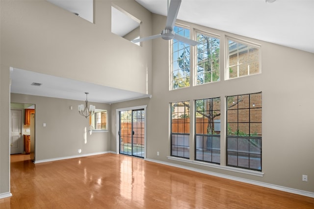 unfurnished living room with hardwood / wood-style flooring, high vaulted ceiling, and an inviting chandelier