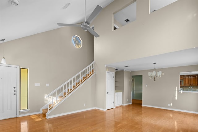 unfurnished living room with beamed ceiling, ceiling fan with notable chandelier, hardwood / wood-style flooring, and high vaulted ceiling