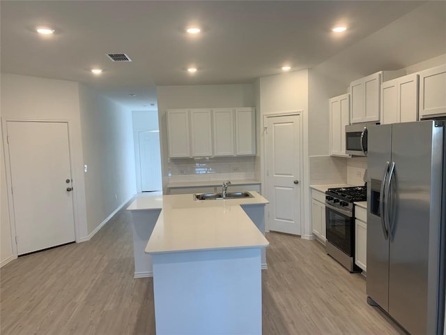 kitchen with appliances with stainless steel finishes, a center island with sink, white cabinetry, and sink