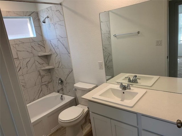 full bathroom featuring vanity, tiled shower / bath combo, and toilet