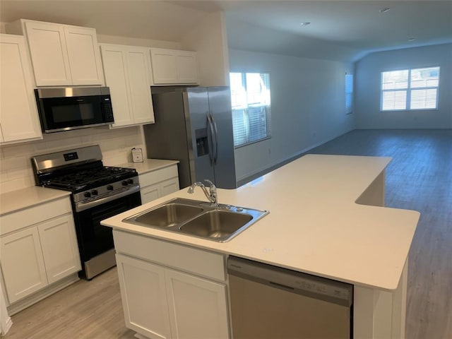 kitchen with sink, backsplash, a center island with sink, white cabinets, and appliances with stainless steel finishes