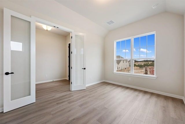 unfurnished bedroom with light hardwood / wood-style floors and vaulted ceiling