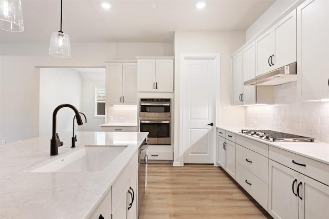 kitchen with sink, pendant lighting, decorative backsplash, white cabinets, and appliances with stainless steel finishes