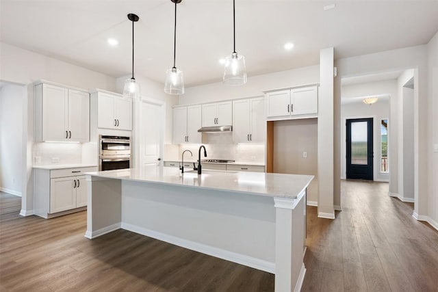 kitchen with white cabinets, pendant lighting, wood-type flooring, and an island with sink