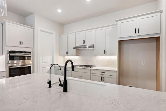 kitchen with decorative backsplash, white cabinets, and appliances with stainless steel finishes