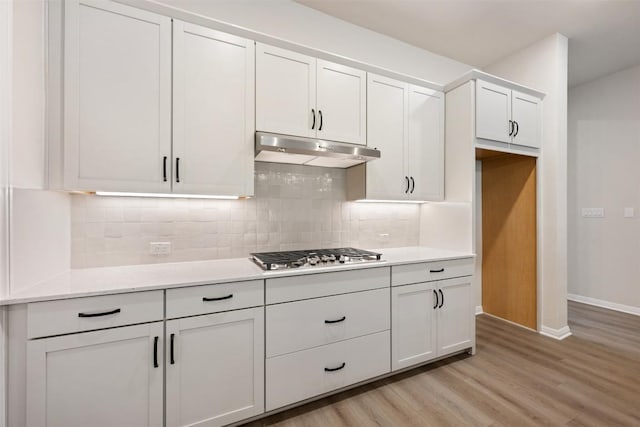 kitchen featuring white cabinets, light wood-type flooring, stainless steel gas cooktop, and backsplash