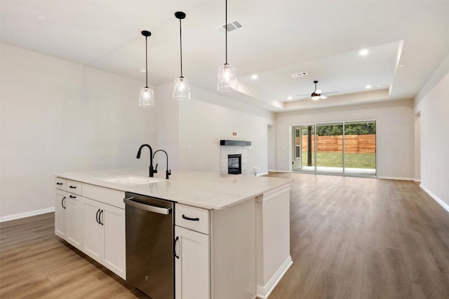 kitchen with stainless steel dishwasher, a raised ceiling, ceiling fan, sink, and white cabinets