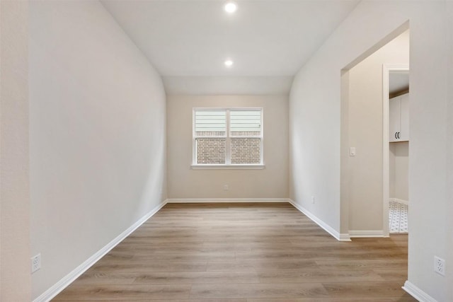 unfurnished room with light hardwood / wood-style floors and lofted ceiling