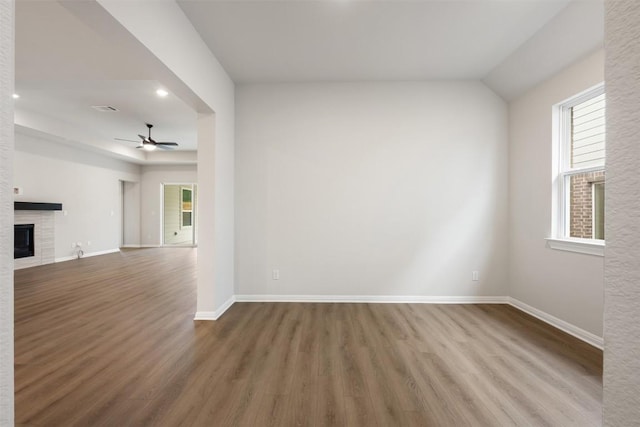 unfurnished room with hardwood / wood-style flooring, ceiling fan, and a tiled fireplace