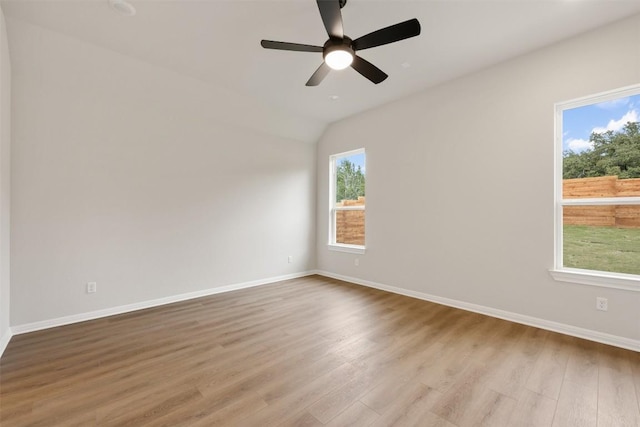 spare room with light hardwood / wood-style flooring, vaulted ceiling, plenty of natural light, and ceiling fan