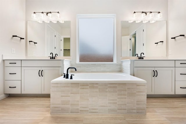 bathroom with vanity and a relaxing tiled tub