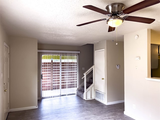 empty room featuring a textured ceiling, dark wood-type flooring, and ceiling fan