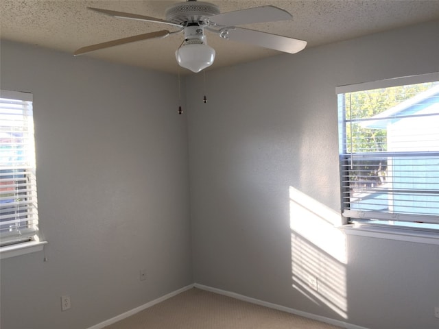 empty room featuring a textured ceiling, carpet, a healthy amount of sunlight, and ceiling fan