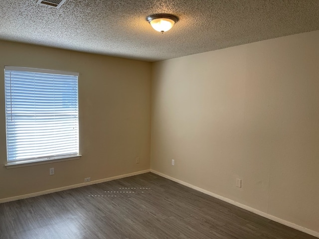 empty room featuring dark hardwood / wood-style flooring and a textured ceiling