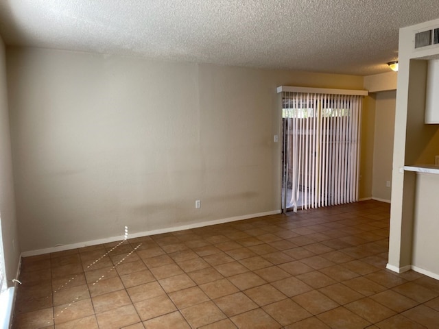 tiled empty room with a textured ceiling