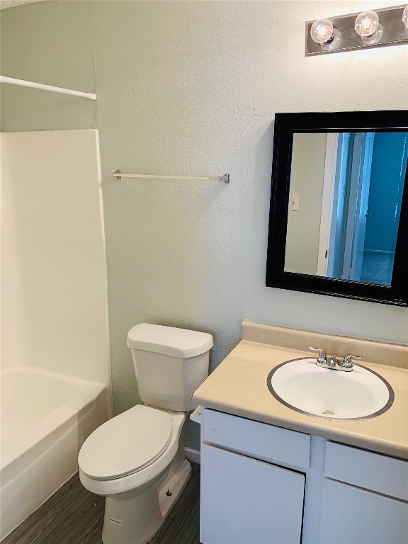 full bathroom with shower / bathing tub combination, hardwood / wood-style floors, vanity, and toilet