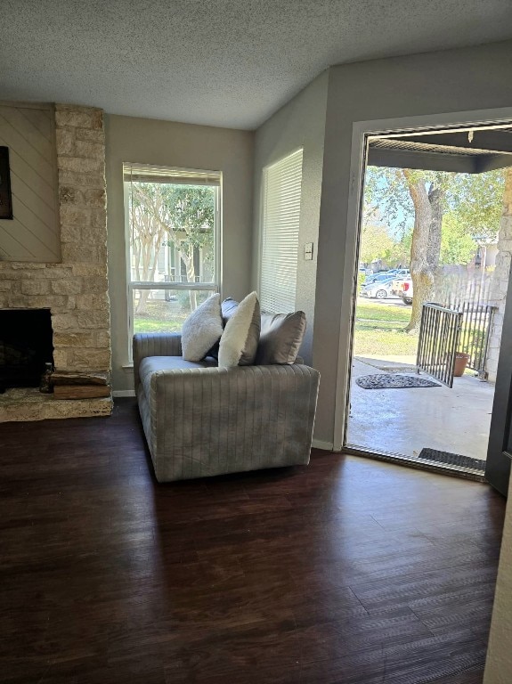 living room featuring dark hardwood / wood-style floors, a fireplace, a healthy amount of sunlight, and a textured ceiling