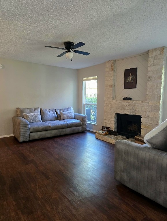 living room featuring a fireplace, ceiling fan, dark hardwood / wood-style flooring, and a textured ceiling