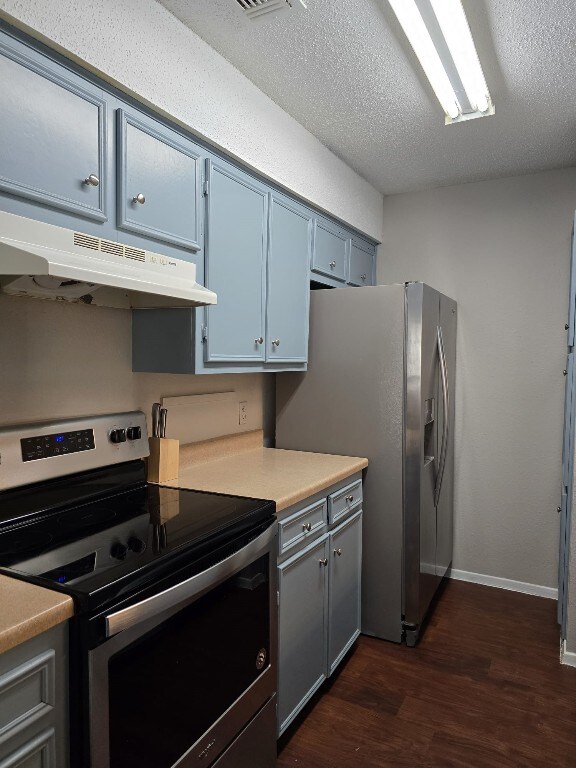 kitchen with dark hardwood / wood-style floors, a textured ceiling, and appliances with stainless steel finishes