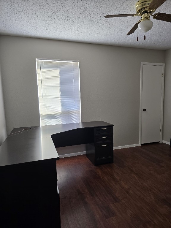 unfurnished office featuring ceiling fan, dark hardwood / wood-style flooring, and a textured ceiling