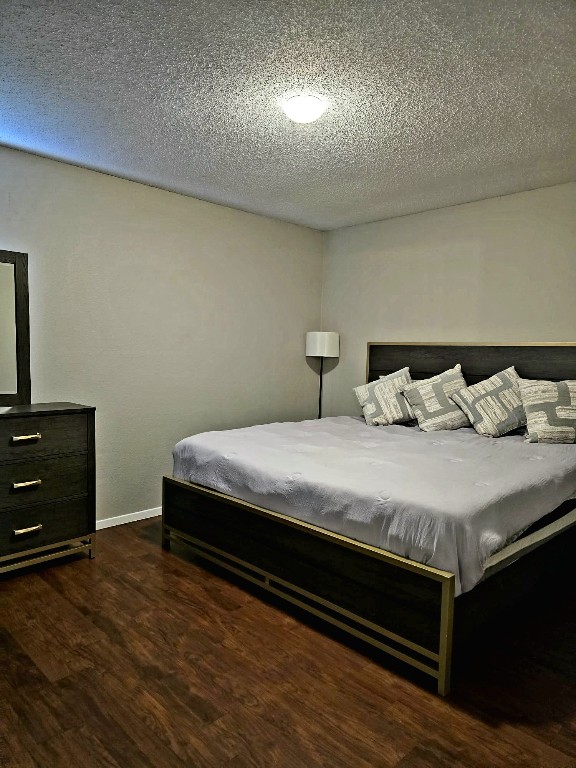 bedroom with dark wood-type flooring and a textured ceiling