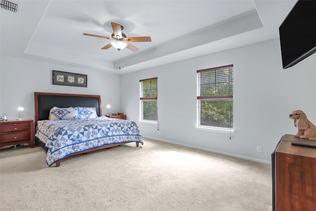 bedroom featuring ceiling fan, light carpet, and a tray ceiling