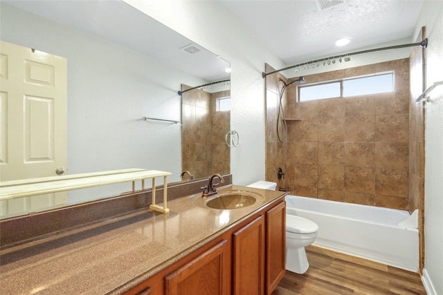 full bathroom featuring toilet, tiled shower / bath, a textured ceiling, hardwood / wood-style flooring, and vanity