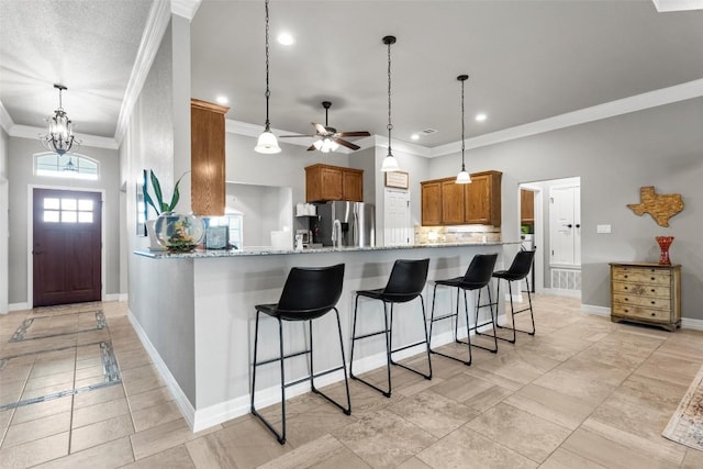 kitchen with crown molding, light stone counters, kitchen peninsula, and stainless steel refrigerator with ice dispenser