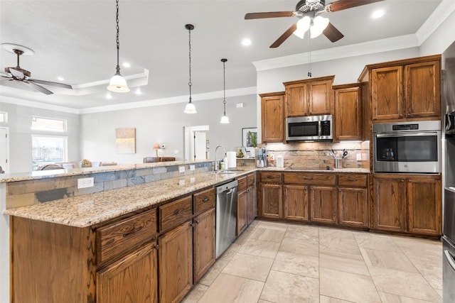 kitchen featuring appliances with stainless steel finishes, hanging light fixtures, backsplash, light stone counters, and a tray ceiling