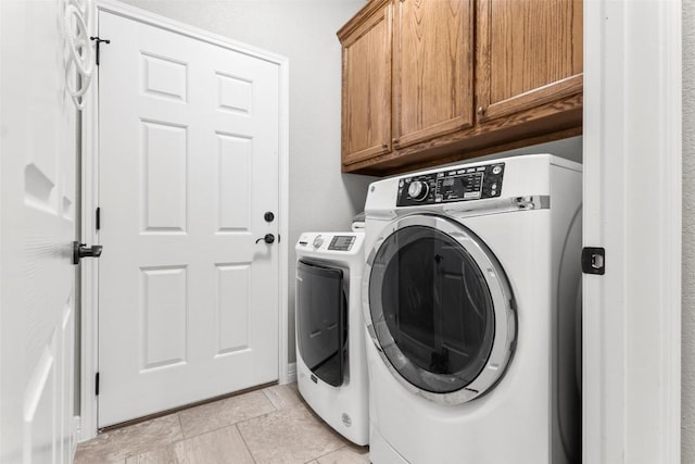 clothes washing area with cabinets, light tile patterned flooring, and independent washer and dryer