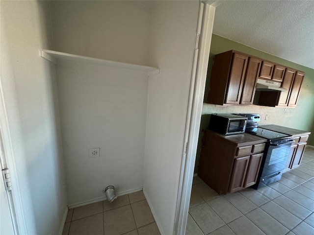 kitchen with a textured ceiling, stainless steel appliances, and light tile patterned flooring